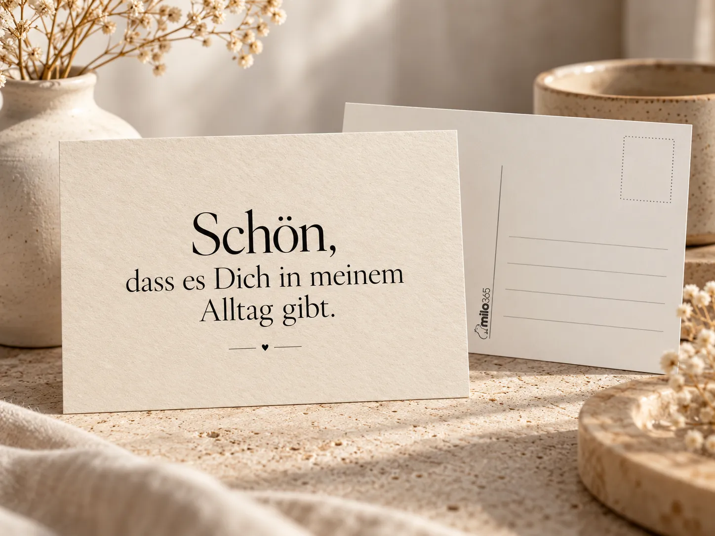 Postkarte „Schön, dass es Dich in meinem Alltag gibt.“: vorn aufgestellt die Vorderseite, dahinter die Rückseite mit Briefmarkenfeld und Adresslinien